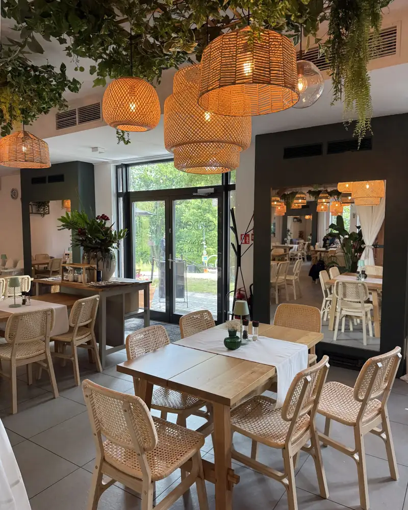 Stoliki pod girlandami zieleni przy wejściu